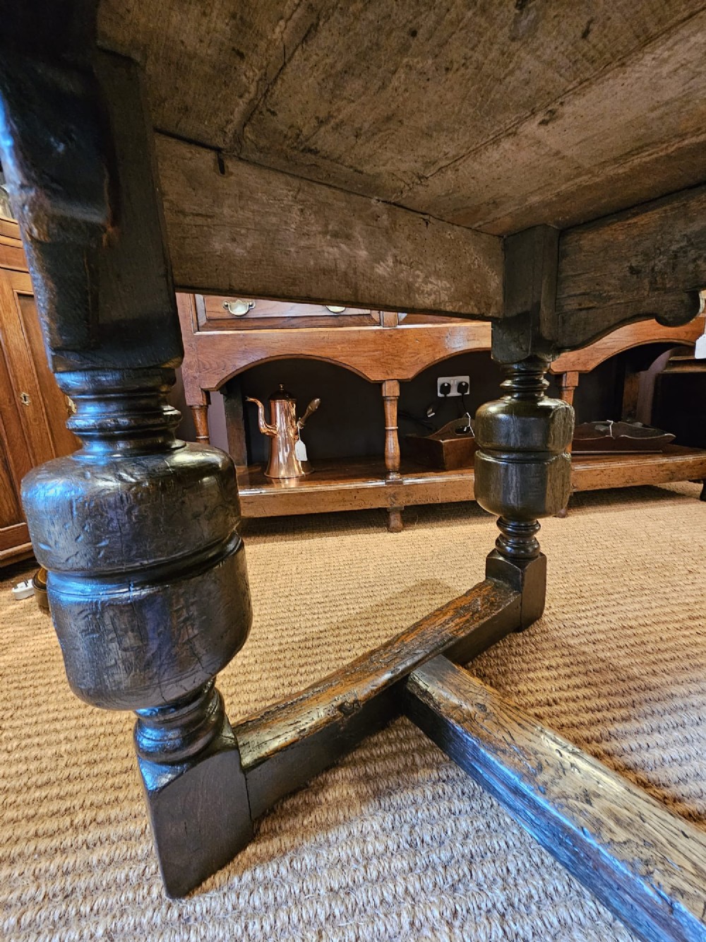 A long George II dark oak refectory dining table featuring a solid plank top, turned legs, and low stretcher rails. View XII