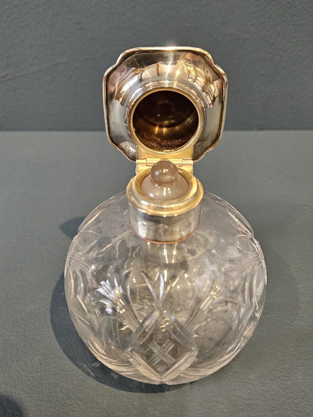 A round cut crystal glass scent bottle with a sterling silver neck collar and a square hinged silver lid featuring an inlaid tortoiseshell top. View III