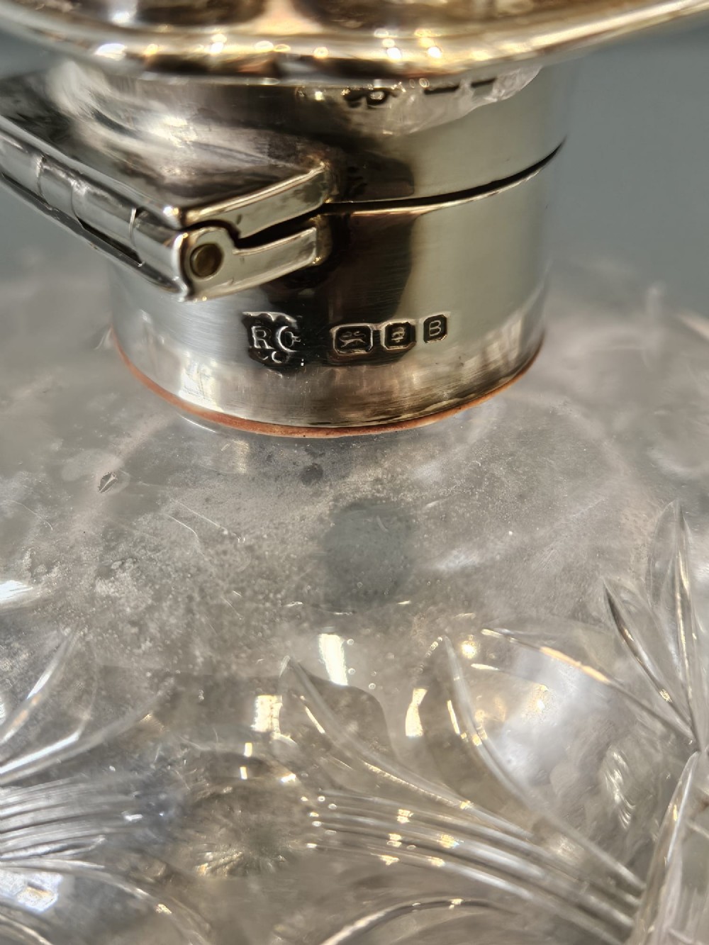 A round cut crystal glass scent bottle with a sterling silver neck collar and a square hinged silver lid featuring an inlaid tortoiseshell top. View V