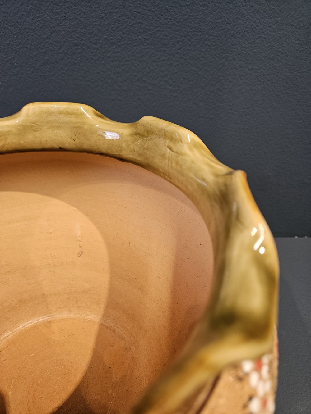A Victorian Doulton Lambeth stoneware jardiniere featuring a wavy crimped rim, textured lace-impressed floral pattern in white and terracotta red on an ochre ground, and a dark brown upper band. View III
