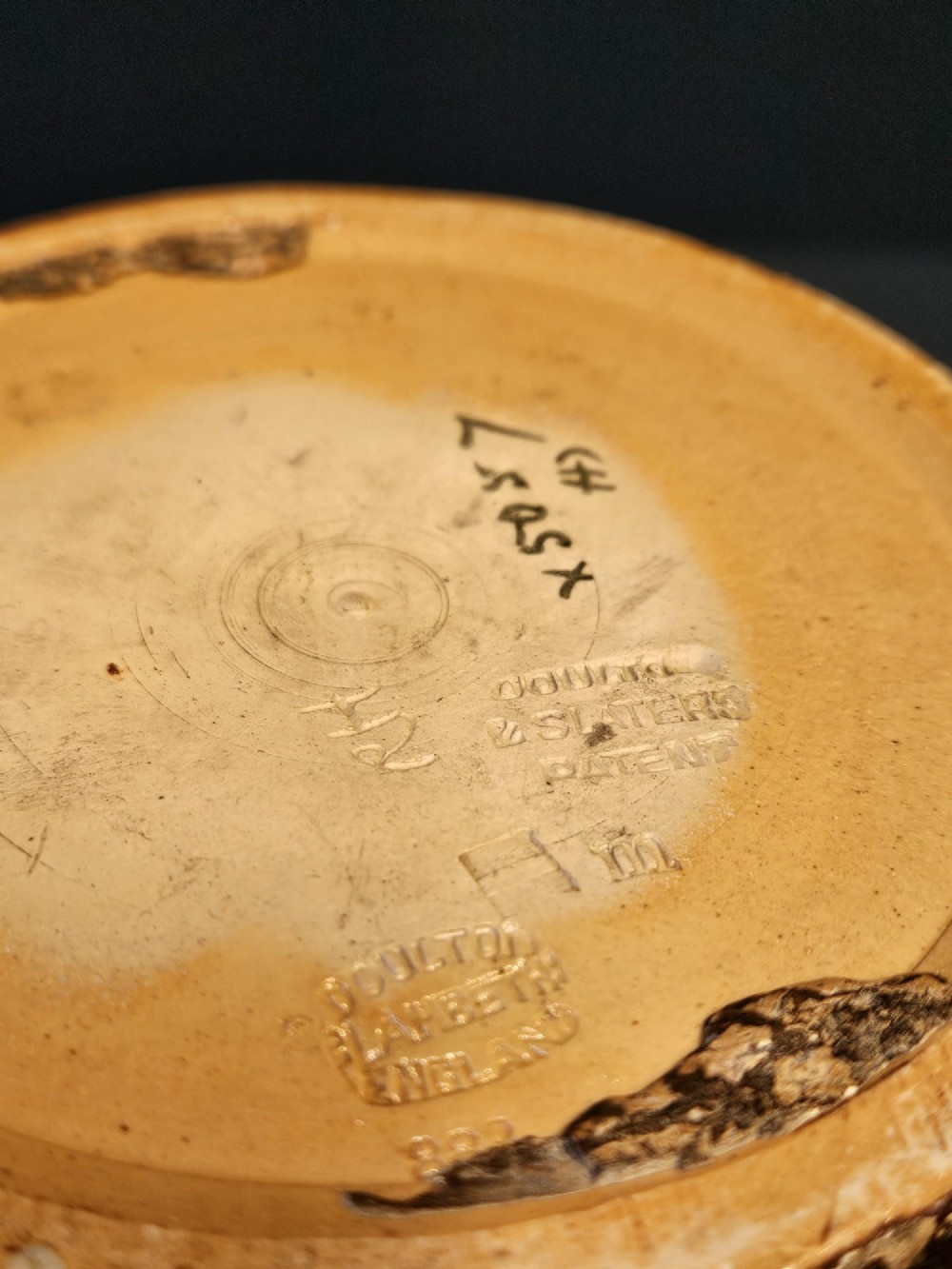 A Victorian Doulton Lambeth stoneware jardiniere featuring a wavy crimped rim, textured lace-impressed floral pattern in white and terracotta red on an ochre ground, and a dark brown upper band. View VI