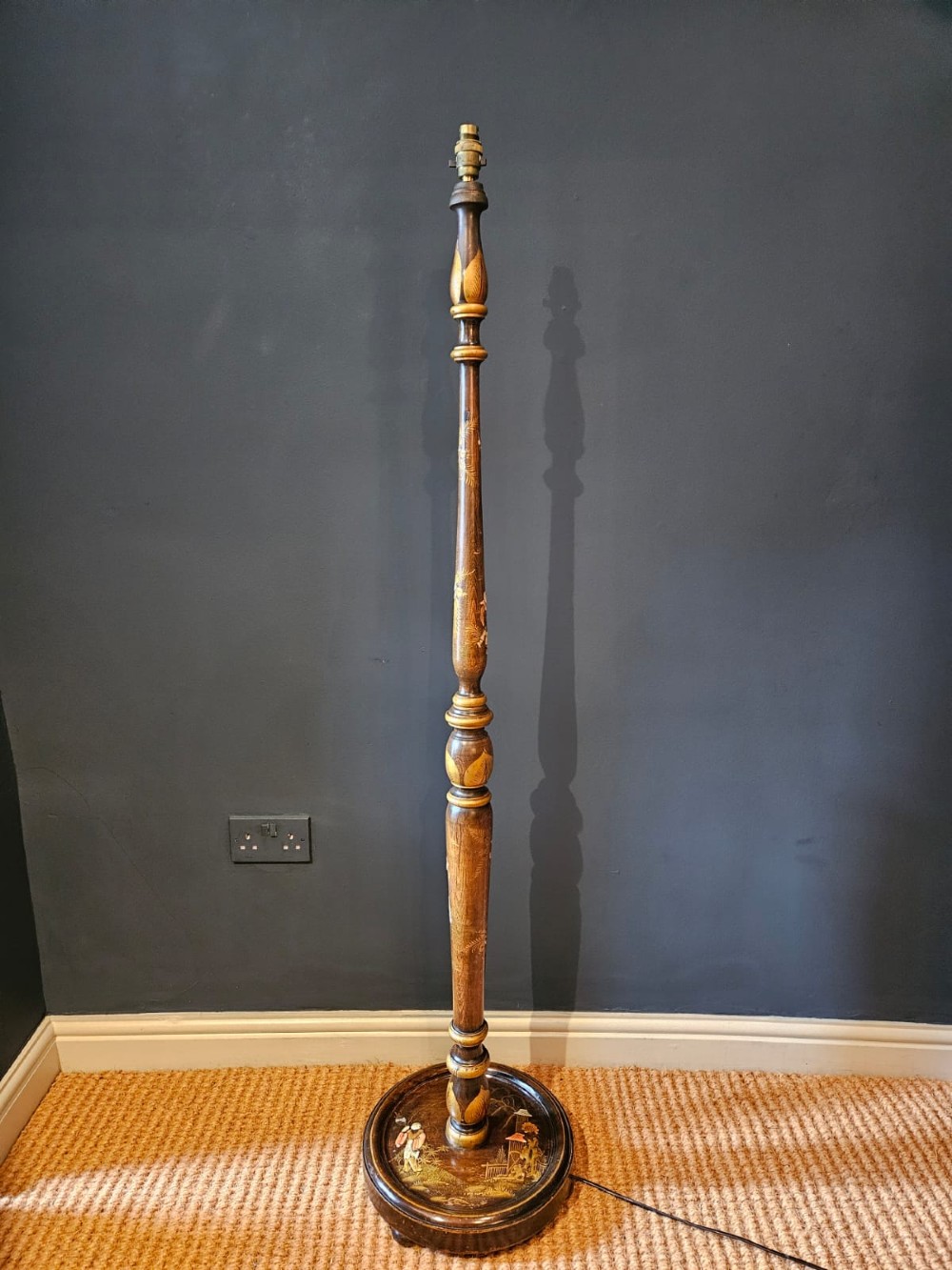 A turned 1920s Chinoiserie standard lamp made from dark lacquered wood decorated with gold painted oriental figures and motifs on a circular base.