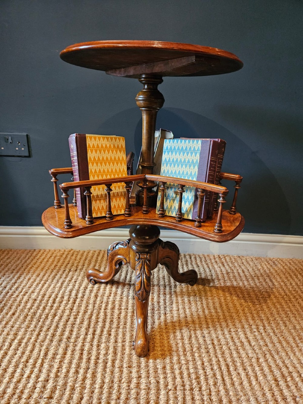A Victorian burr walnut revolving book table with a round top, three spindle-railed book compartments, a turned central stem, and carved tripod legs. View II