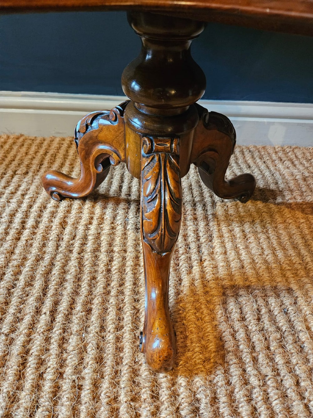A Victorian burr walnut revolving book table with a round top, three spindle-railed book compartments, a turned central stem, and carved tripod legs. View IV