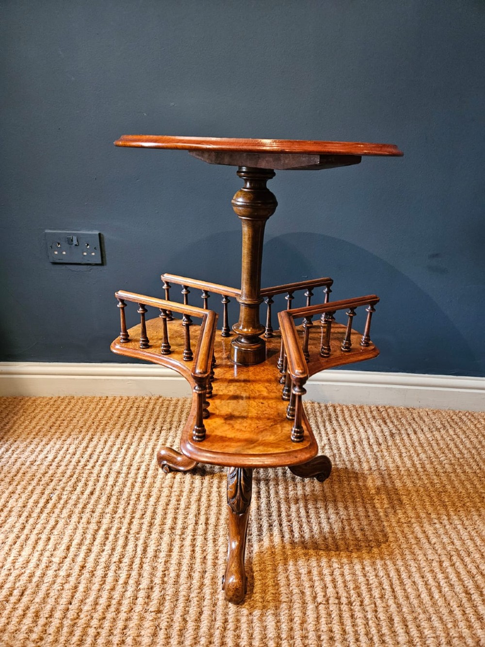 A Victorian burr walnut revolving book table with a round top, three spindle-railed book compartments, a turned central stem, and carved tripod legs. View VII