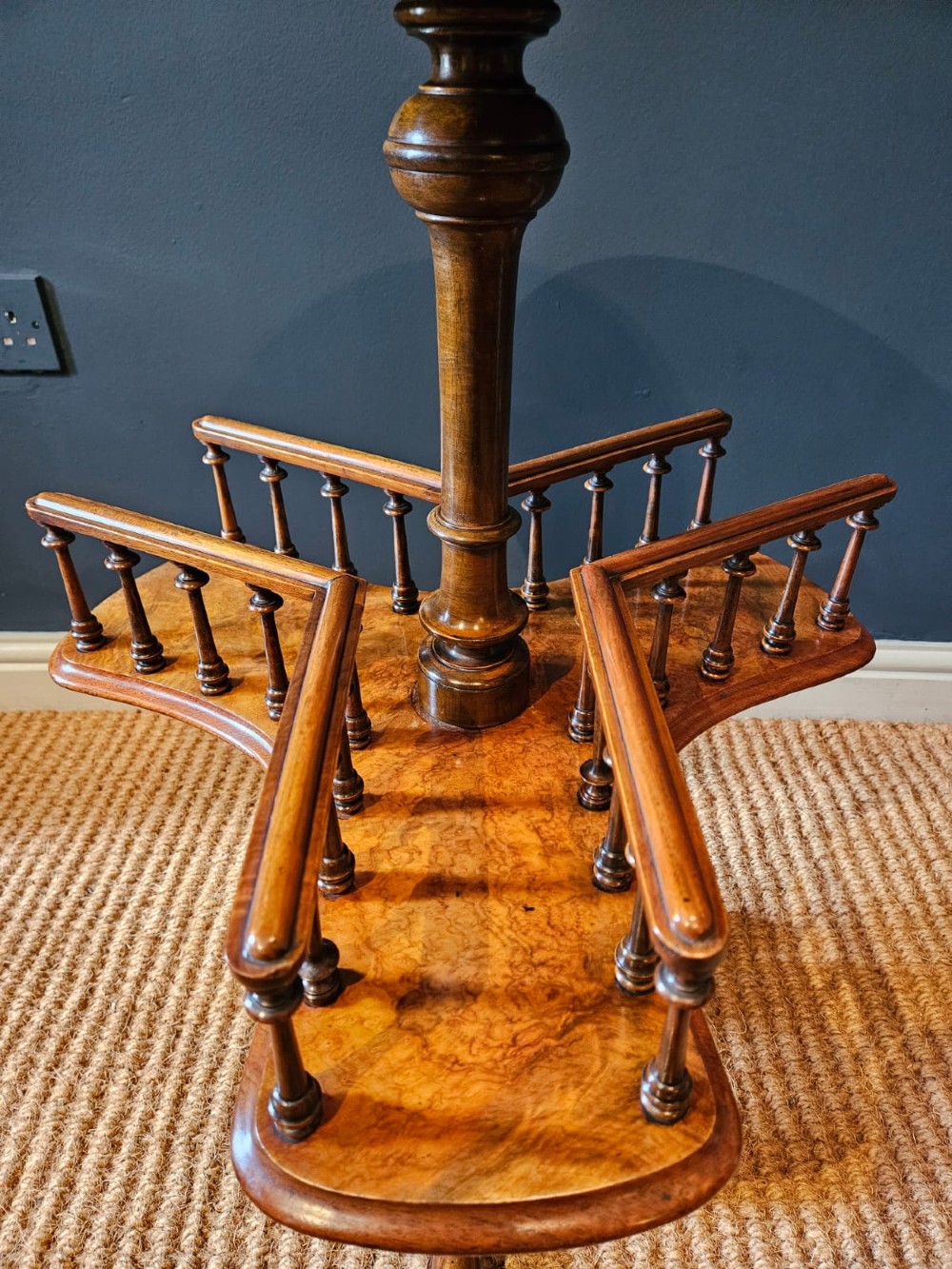 A Victorian burr walnut revolving book table with a round top, three spindle-railed book compartments, a turned central stem, and carved tripod legs. View VIII