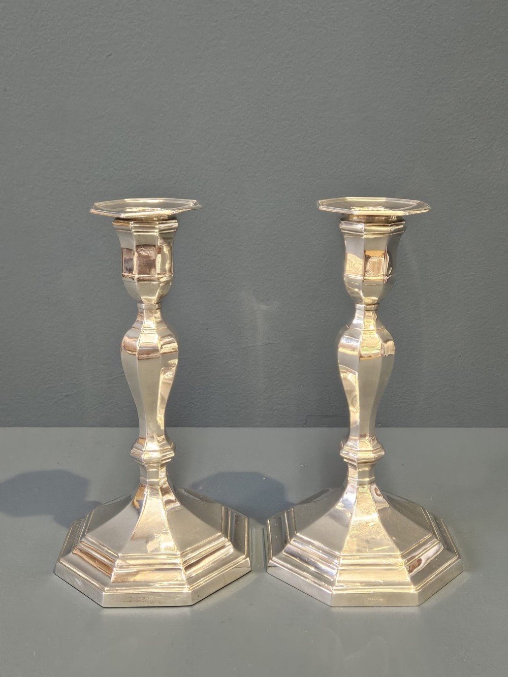 A pair of polished silver candlesticks featuring octagonal faceted bases and baluster stems.