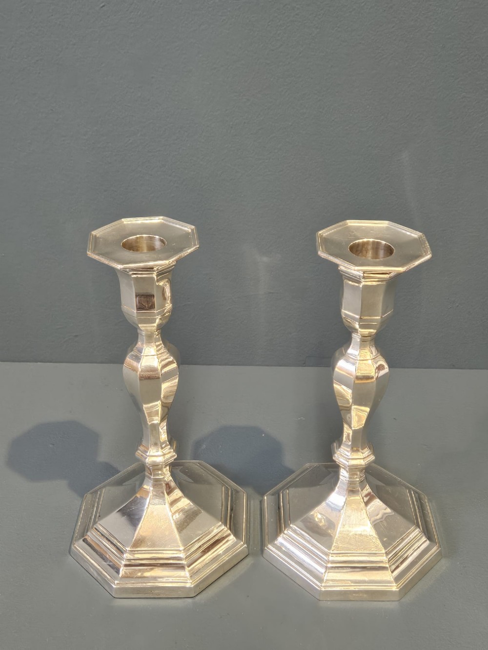 A pair of polished silver candlesticks featuring octagonal faceted bases and baluster stems. View II