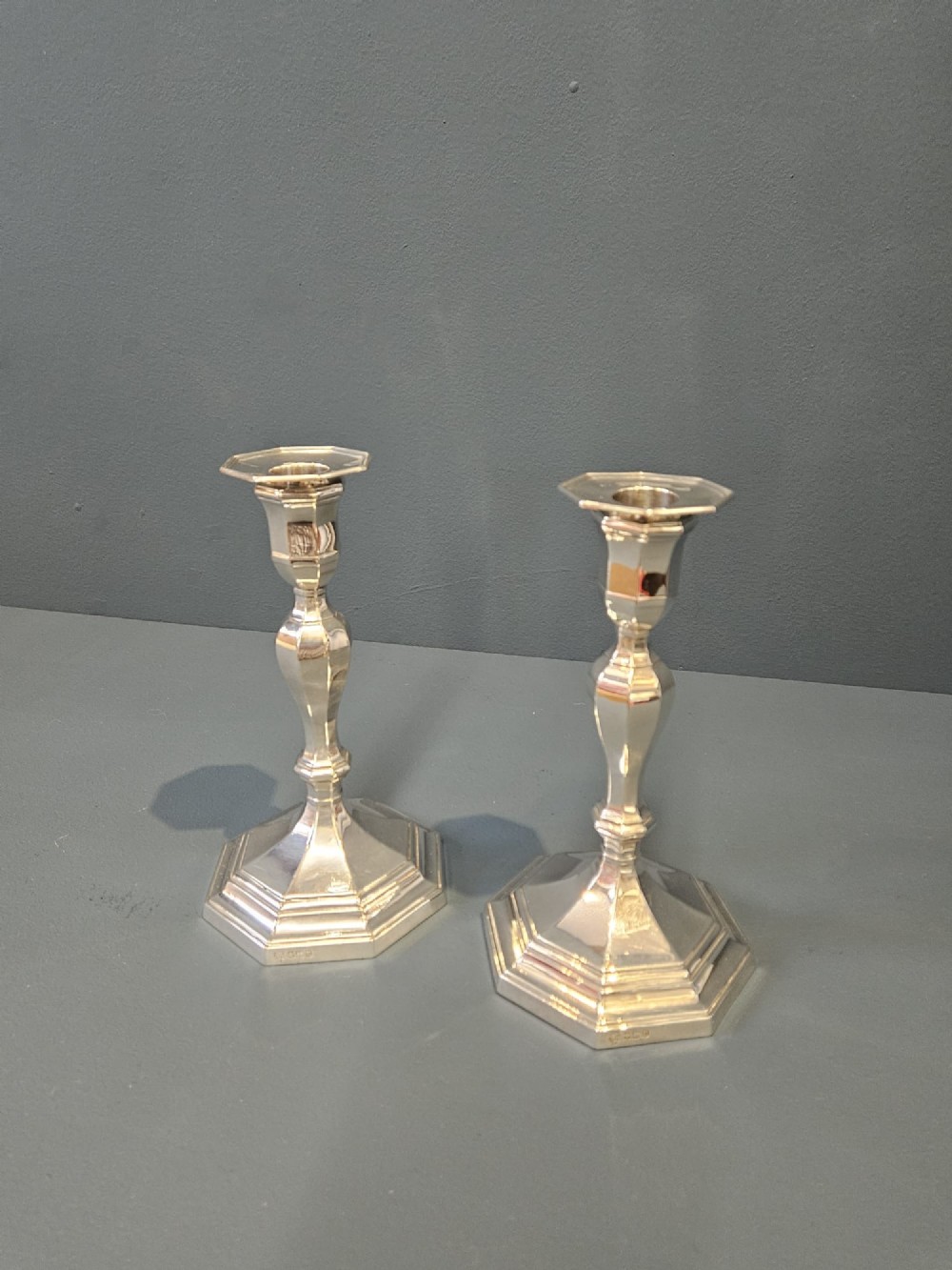 A pair of polished silver candlesticks featuring octagonal faceted bases and baluster stems. View VI