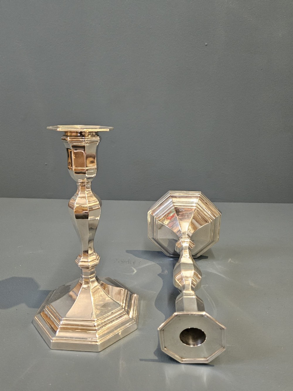 A pair of polished silver candlesticks featuring octagonal faceted bases and baluster stems. View VII