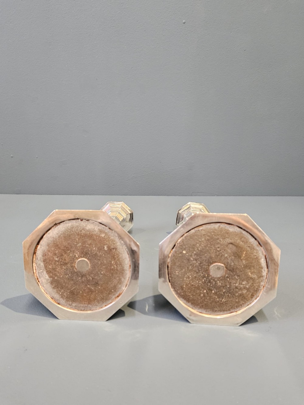 A pair of polished silver candlesticks featuring octagonal faceted bases and baluster stems. View VIII