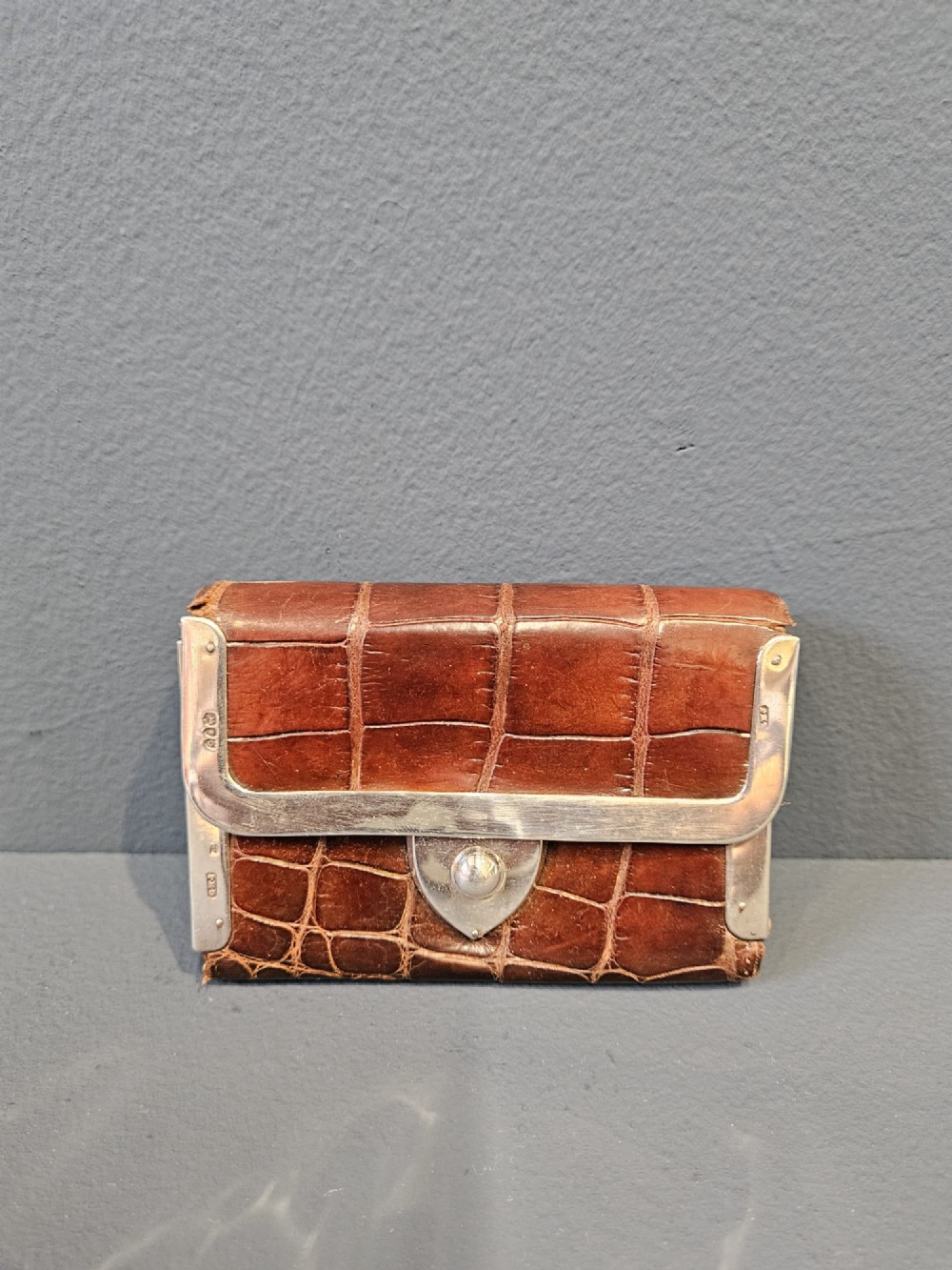 A small rectangular brown crocodile skin purse with hallmarked sterling silver rim mounts and a central push-button clasp.