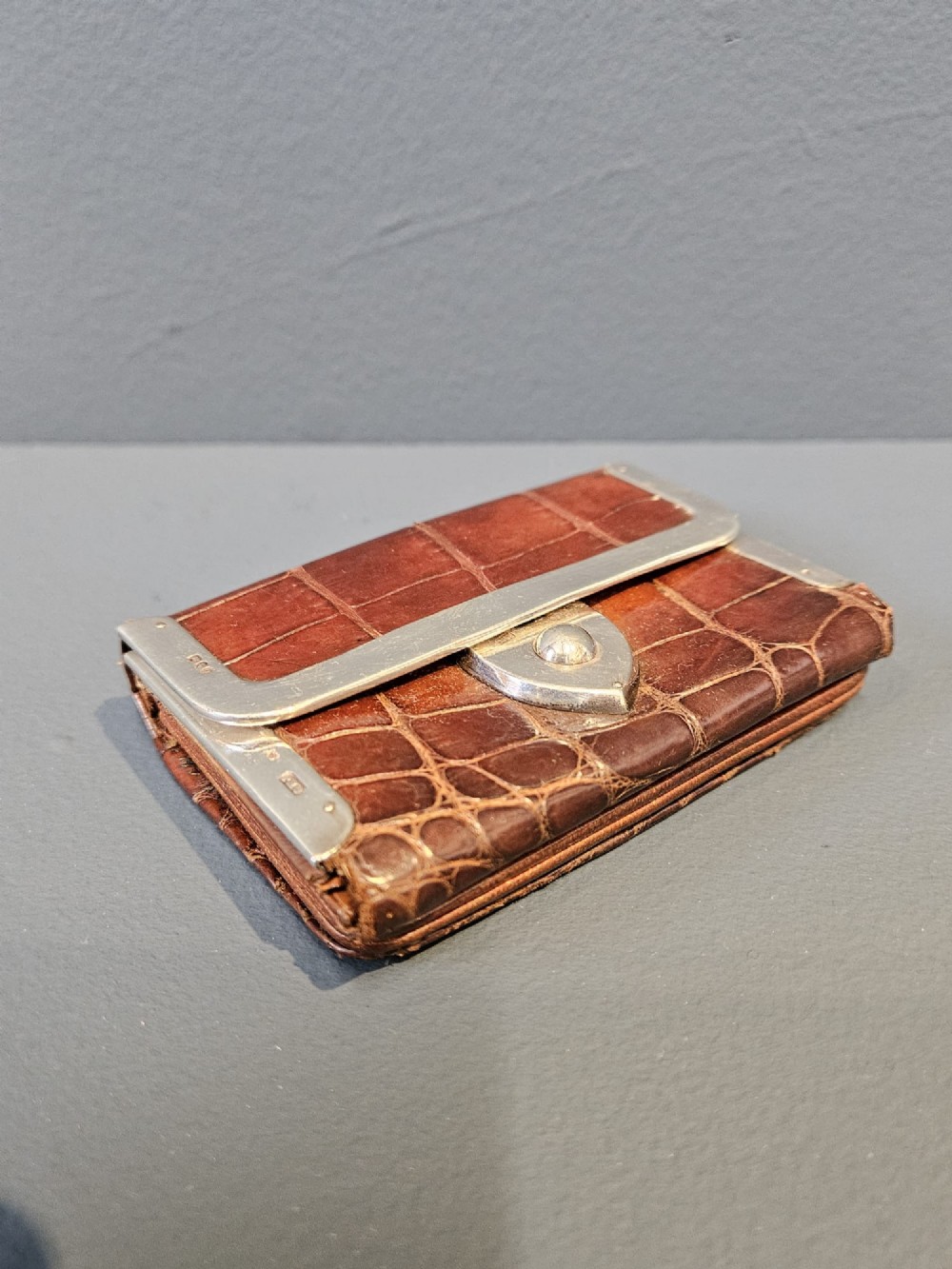 A small rectangular brown crocodile skin purse with hallmarked sterling silver rim mounts and a central push-button clasp. View II