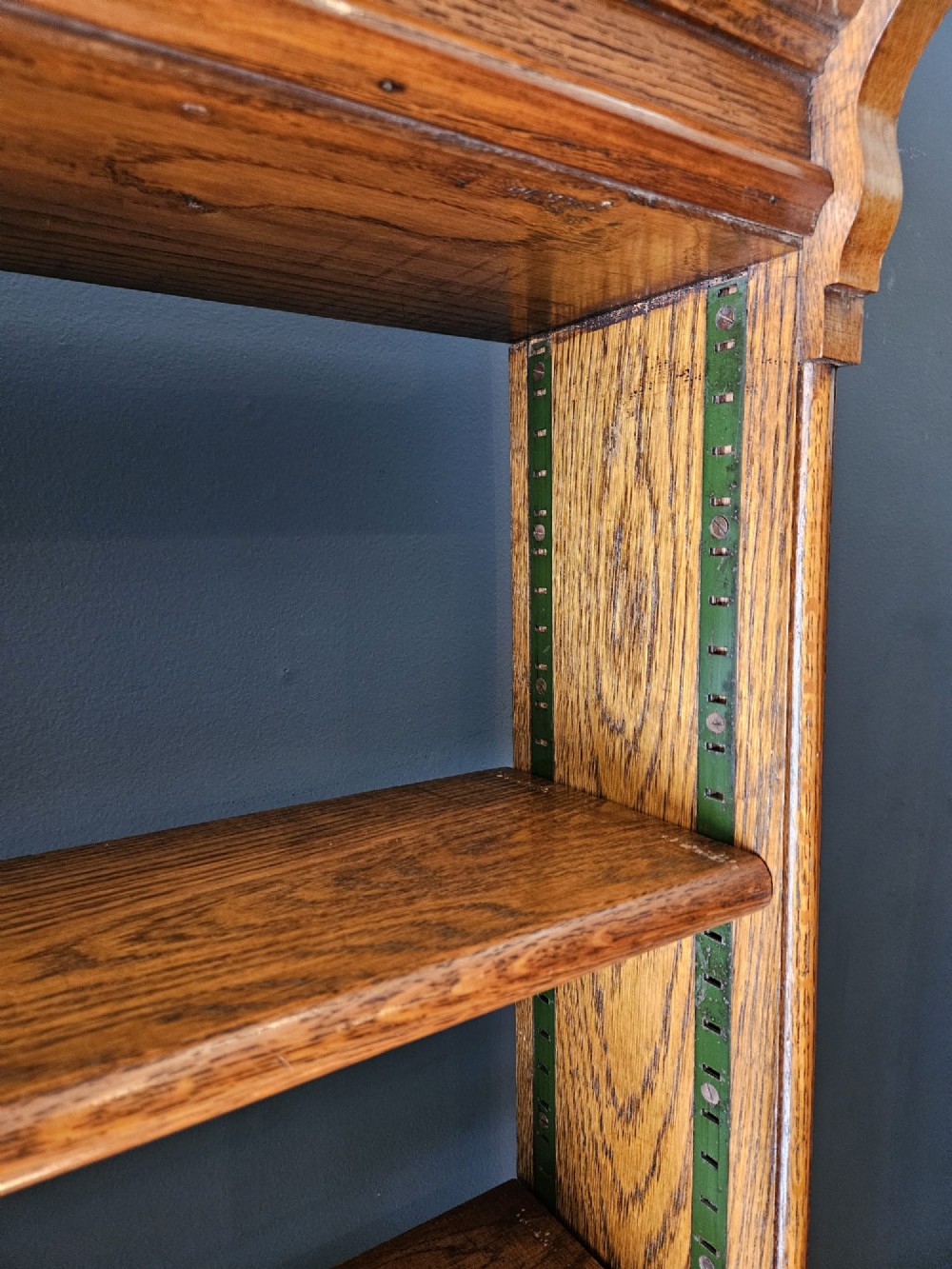A tall Edwardian oak open bookcase featuring six tiers of shelving with carved egg and dart moulding along the top frieze. View III