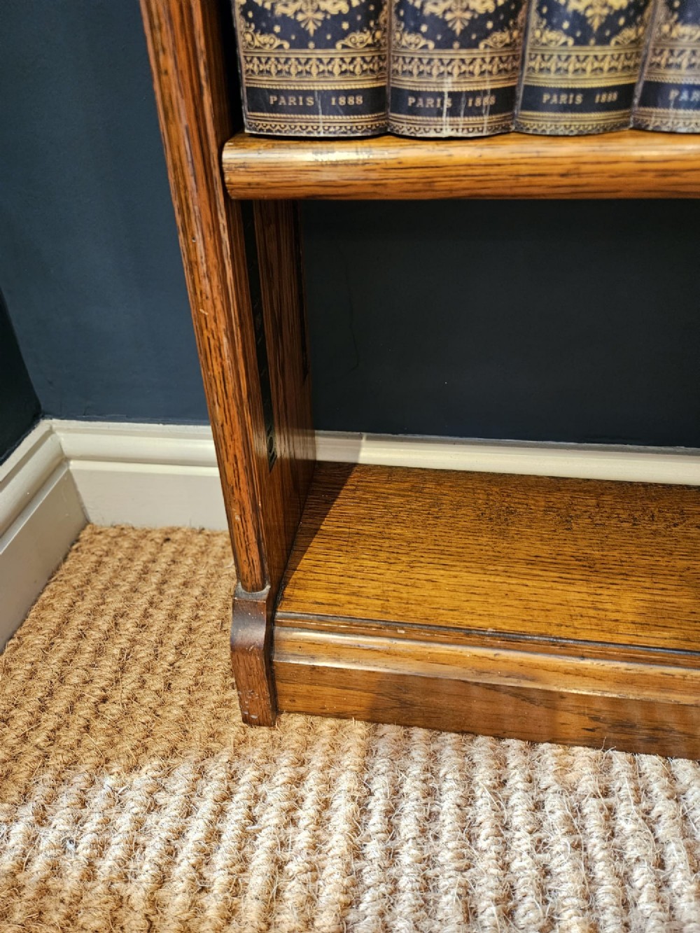A tall Edwardian oak open bookcase featuring six tiers of shelving with carved egg and dart moulding along the top frieze. View V