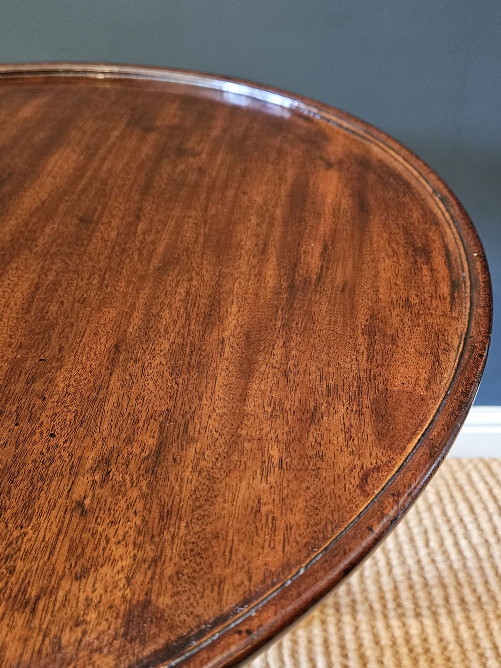 A George II red walnut tripod table featuring a circular dished top set upon a turned central column and three cabriole legs with pad feet. View VII