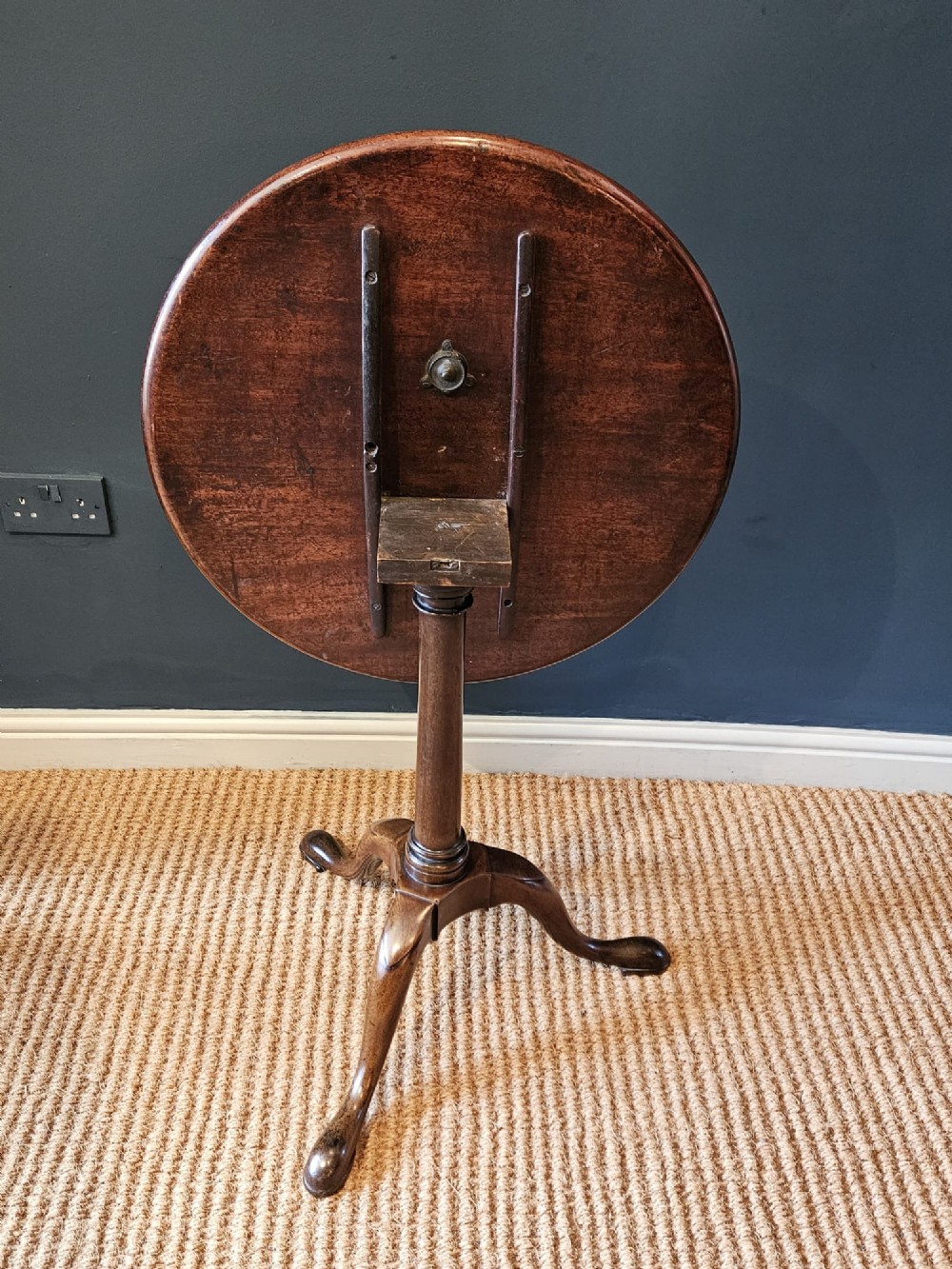 A George II red walnut tripod table featuring a circular dished top set upon a turned central column and three cabriole legs with pad feet. View VIII