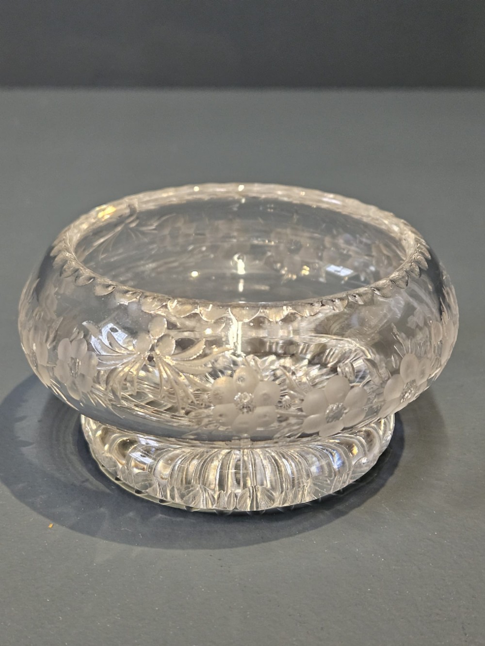 A clear cut glass round jar with a silver-rimmed lid covered in bright green engine-turned enamel and finished with a silver finial. View II