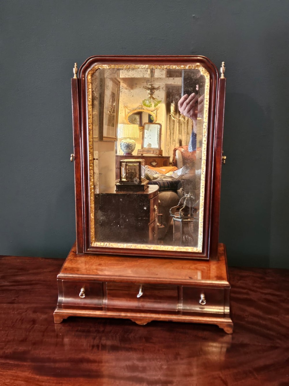 A George II mahogany toilet mirror featuring a swivelling glass plate with a gilded interior moulding, supported on vertical uprights above a drawer base. View II