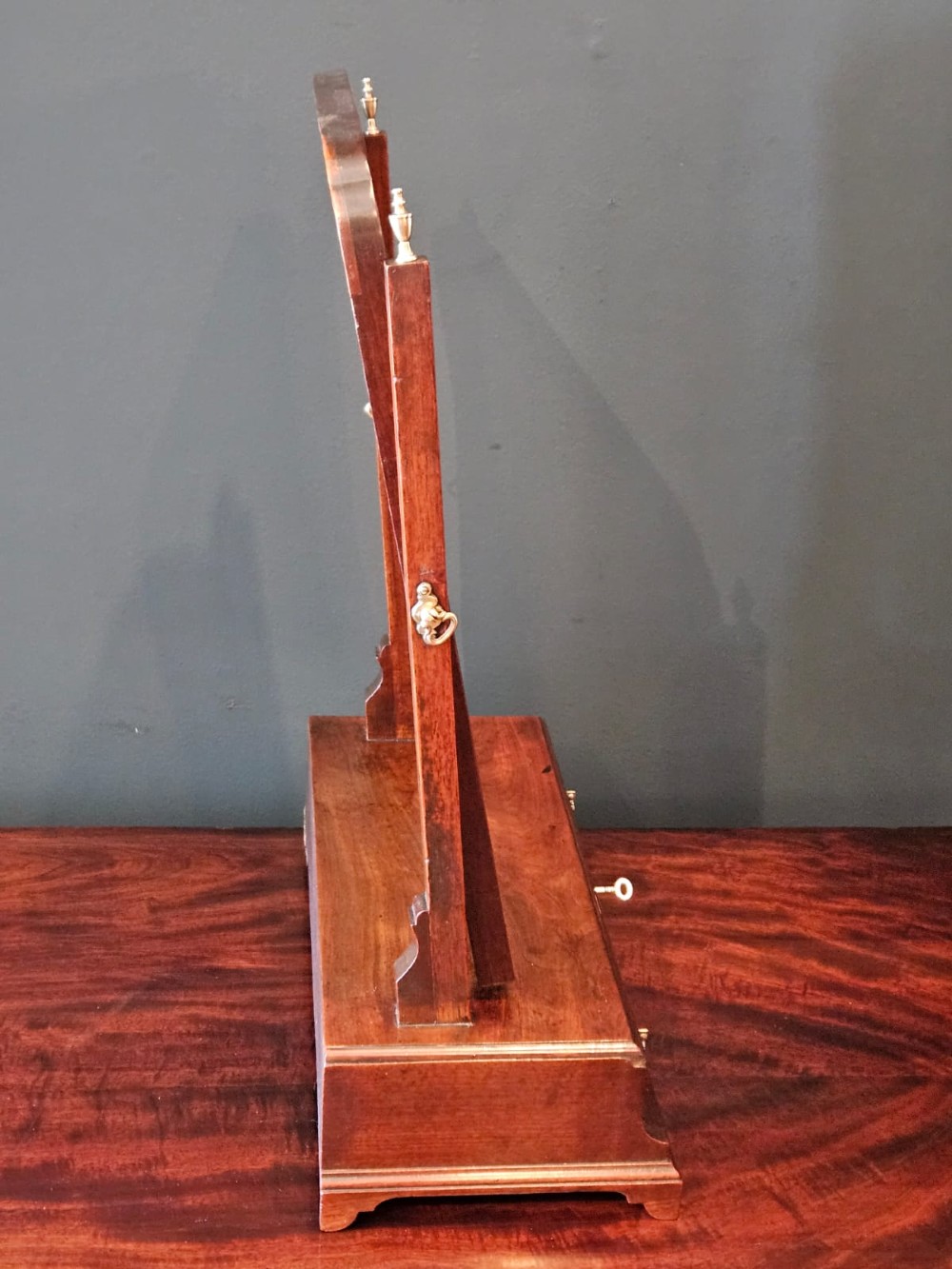 A George II mahogany toilet mirror featuring a swivelling glass plate with a gilded interior moulding, supported on vertical uprights above a drawer base. View VI