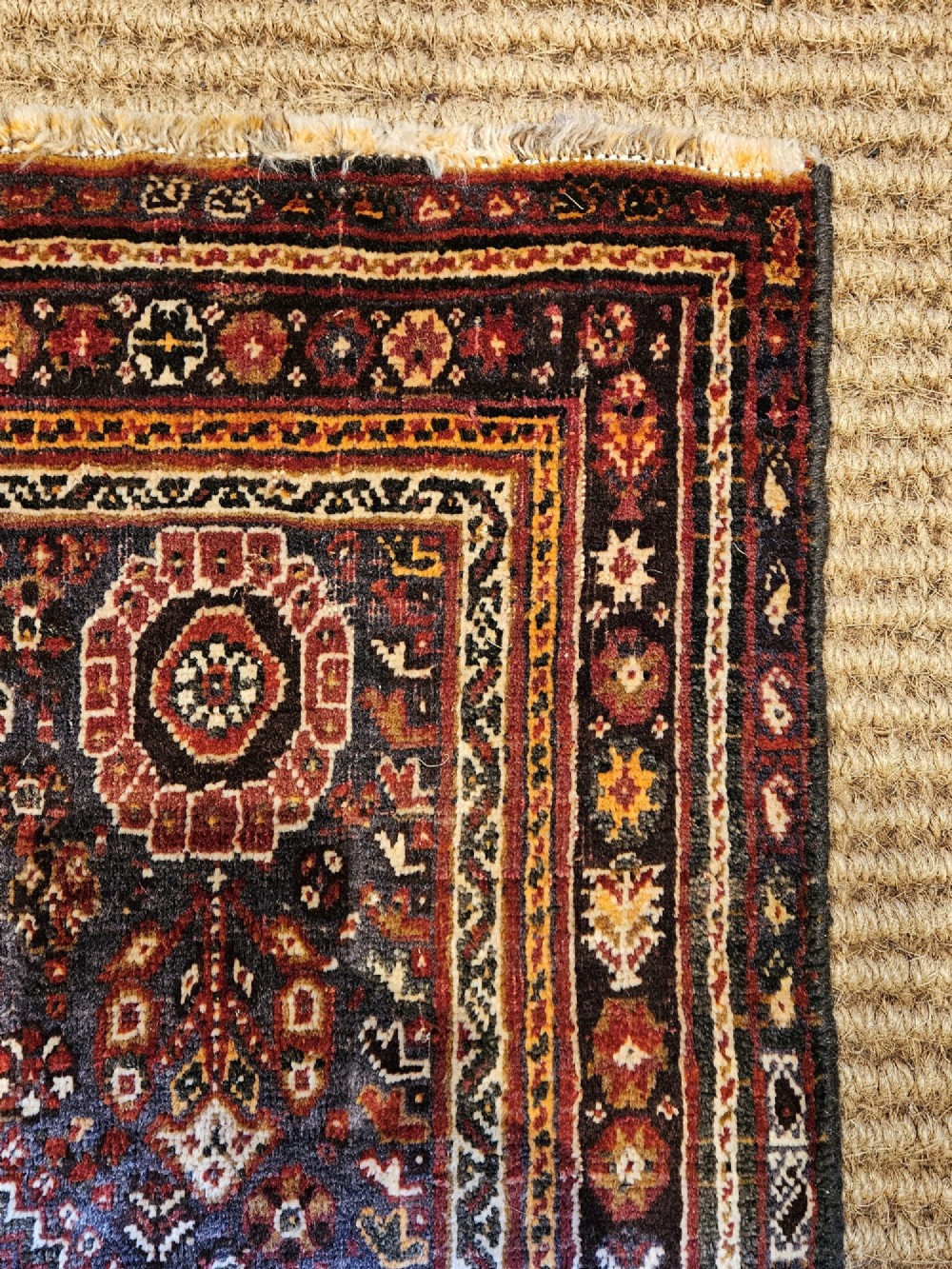 A rectangular hand-knotted Persian rug featuring a rust-red field with a central diamond medallion, navy blue accents, and a detailed multi-tiered floral border. View II