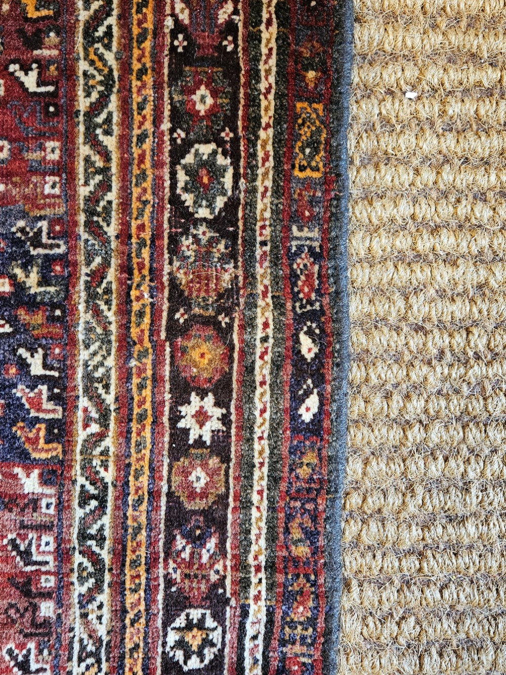 A rectangular hand-knotted Persian rug featuring a rust-red field with a central diamond medallion, navy blue accents, and a detailed multi-tiered floral border. View VI
