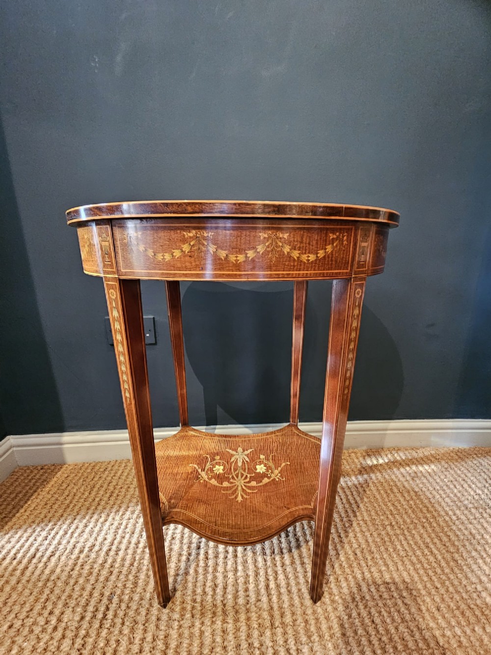 An Edwardian kidney-shaped mahogany occasional table featuring classical marquetry inlay, a single drawer, and an undertier shelf supported by slender tapered legs. View VII