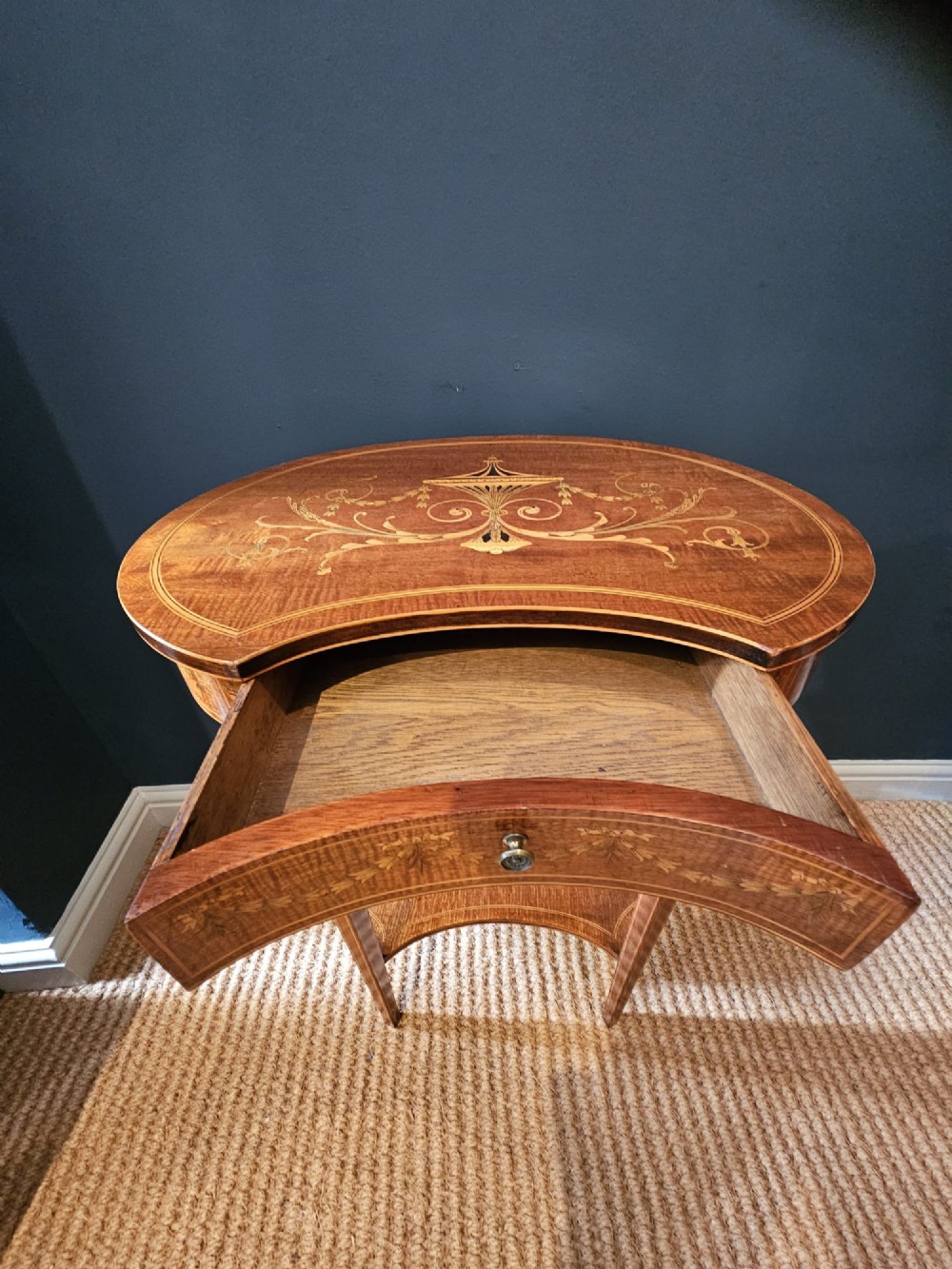 An Edwardian kidney-shaped mahogany occasional table featuring classical marquetry inlay, a single drawer, and an undertier shelf supported by slender tapered legs. View VIII