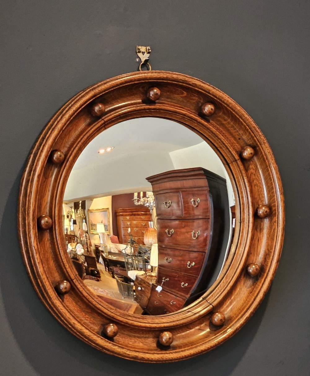 A circular Edwardian oak framed convex mirror featuring a raised moulded border inset with evenly spaced turned wooden spheres. View V
