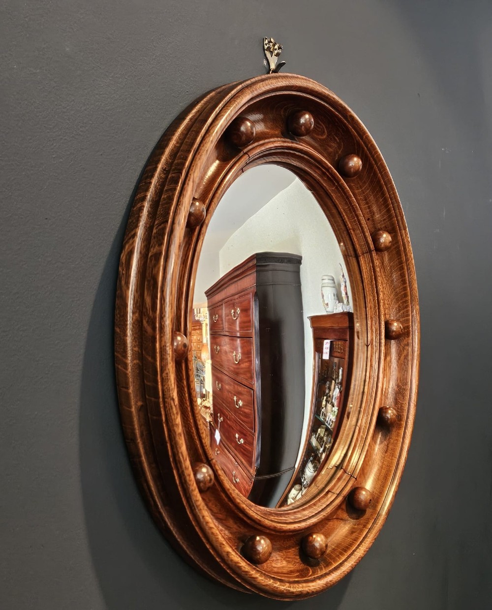 A circular Edwardian oak framed convex mirror featuring a raised moulded border inset with evenly spaced turned wooden spheres. View VI