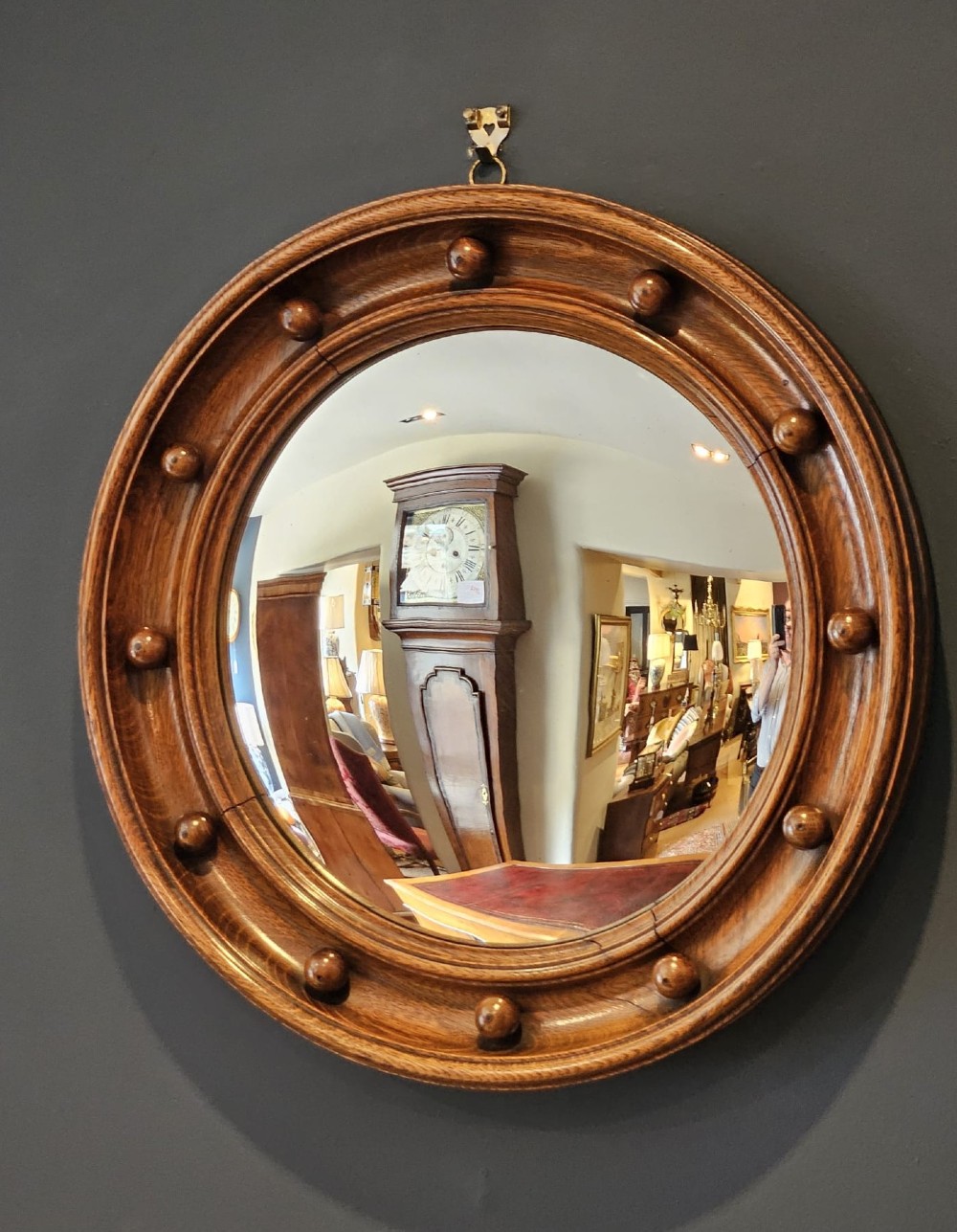 A circular Edwardian oak framed convex mirror featuring a raised moulded border inset with evenly spaced turned wooden spheres. View VII