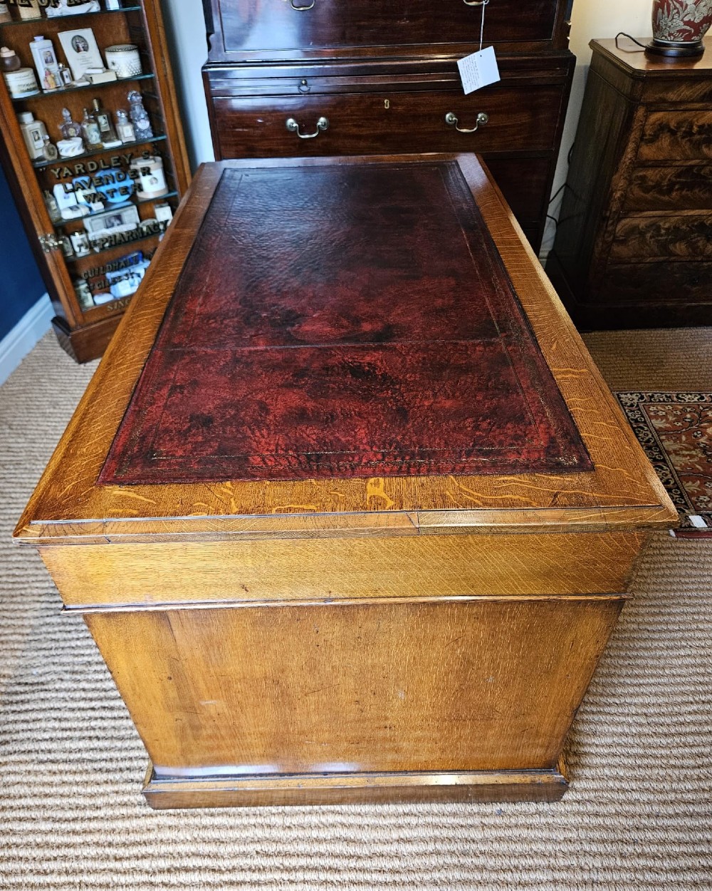 A Victorian oak pedestal desk featuring a red leather inset top, brass swing handles, and twin pedestals housing multiple drawers. View VII
