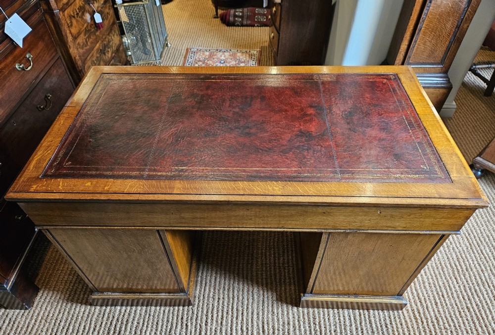 A Victorian oak pedestal desk featuring a red leather inset top, brass swing handles, and twin pedestals housing multiple drawers. View IX