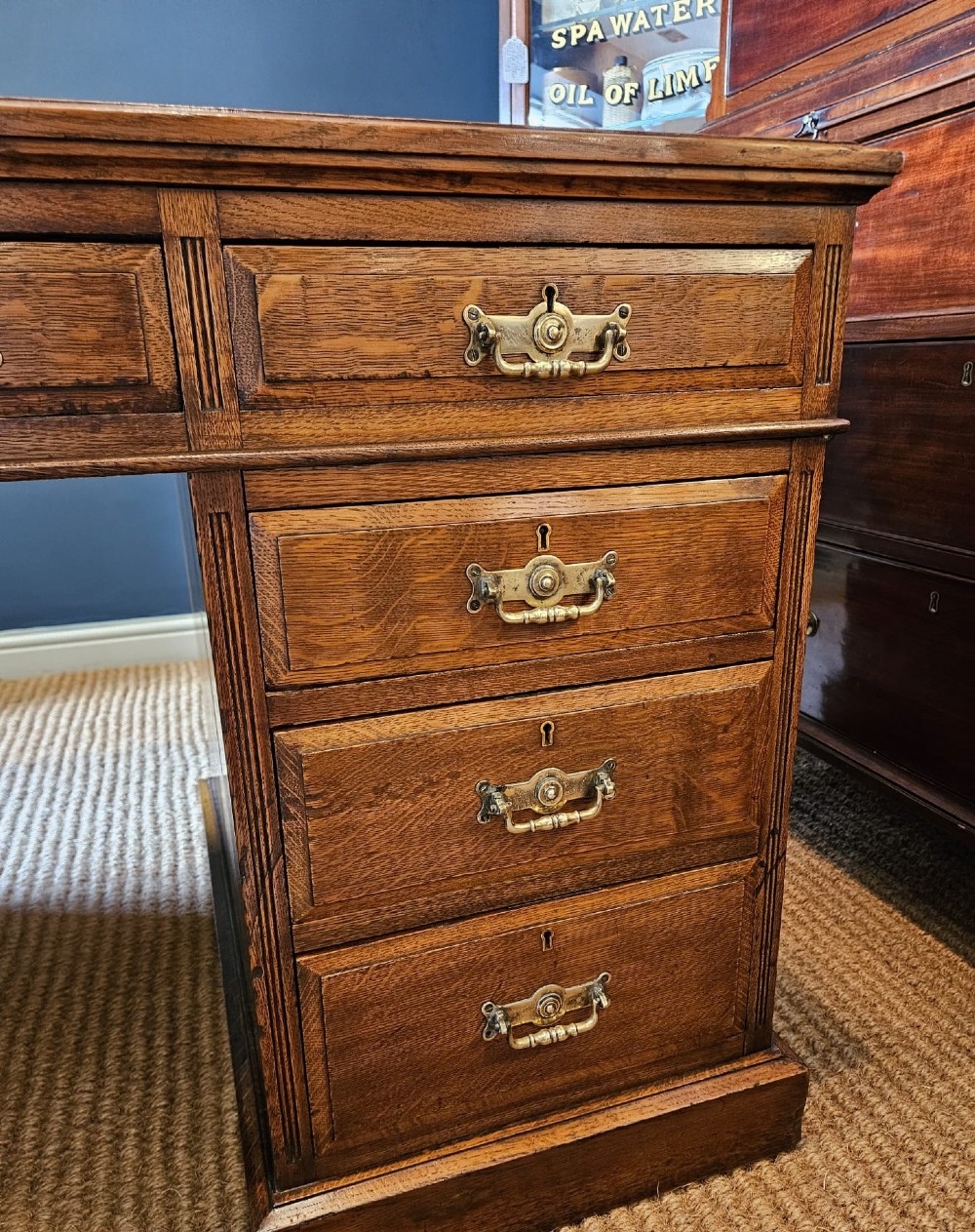 A Victorian oak pedestal desk featuring a red leather inset top, brass swing handles, and twin pedestals housing multiple drawers. View X