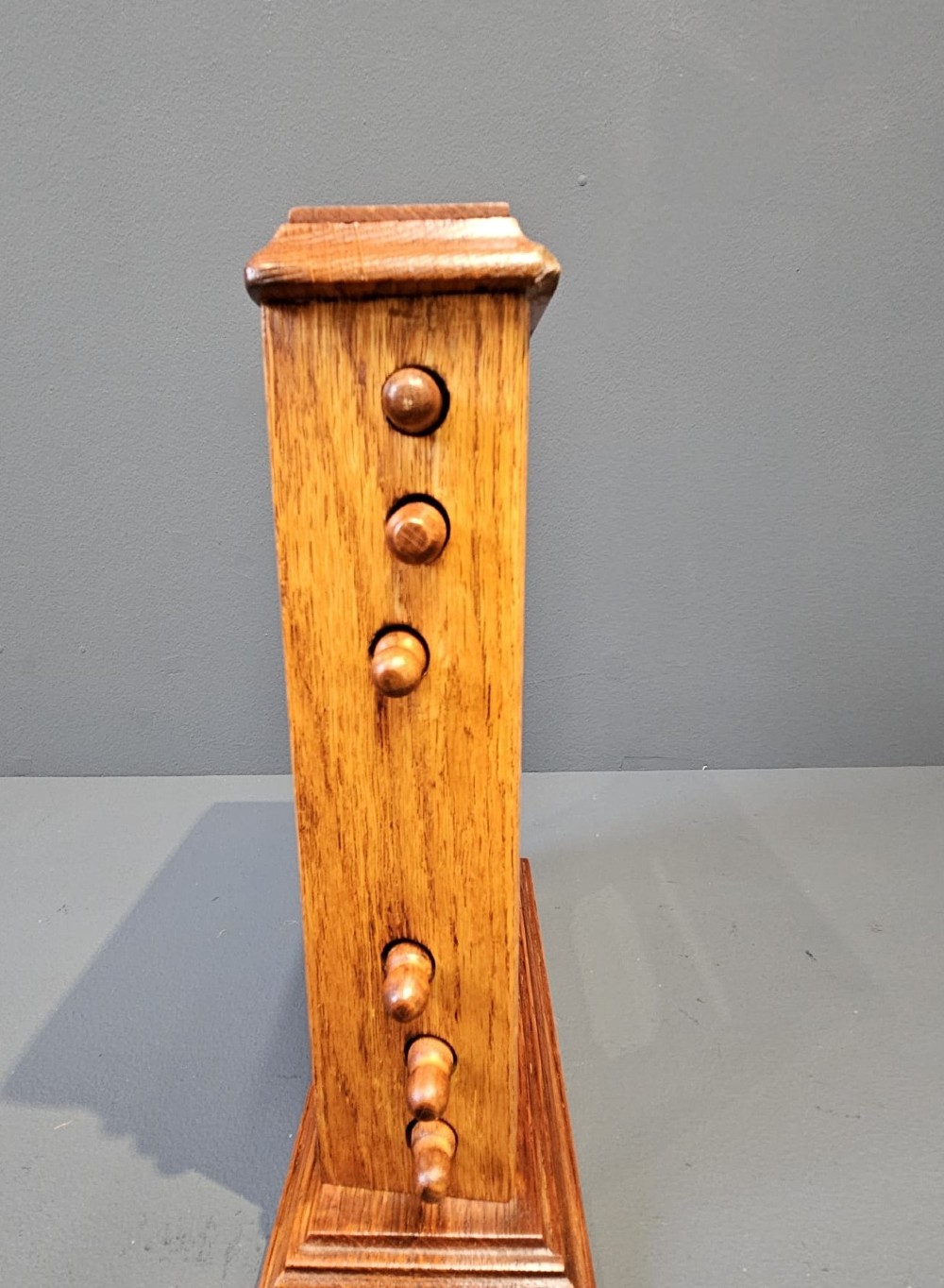 A late Victorian figured oak perpetual desk calendar with turned side knobs and three apertures displaying the day, date, and month. View V
