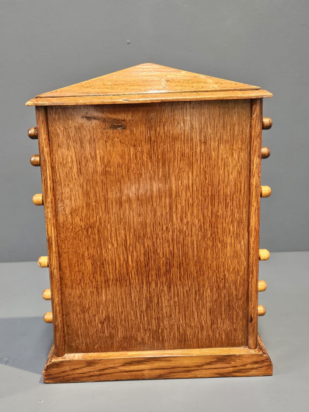 An Edwardian oak perpetual desk calendar featuring side turning knobs, apertures displaying printed day, date, and month rolls, and a gabled pediment top. View VIII