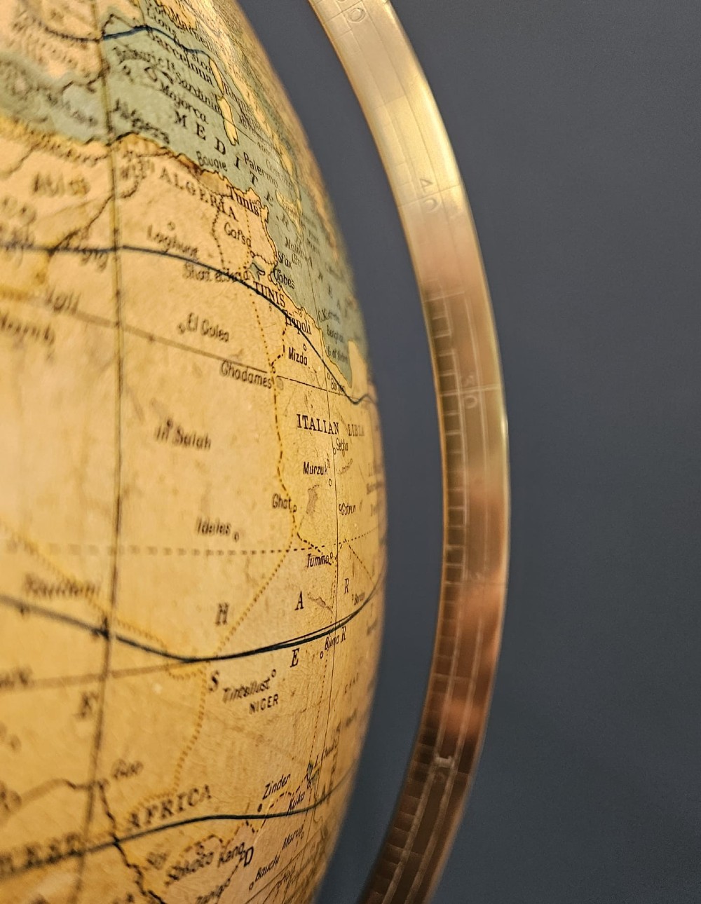 A 1920s terrestrial table globe with printed paper maps mounted on a brass semi-meridian arc and a turned dark walnut base. View II