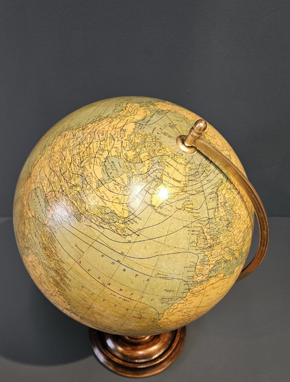 A 1920s terrestrial table globe with printed paper maps mounted on a brass semi-meridian arc and a turned dark walnut base. View VI