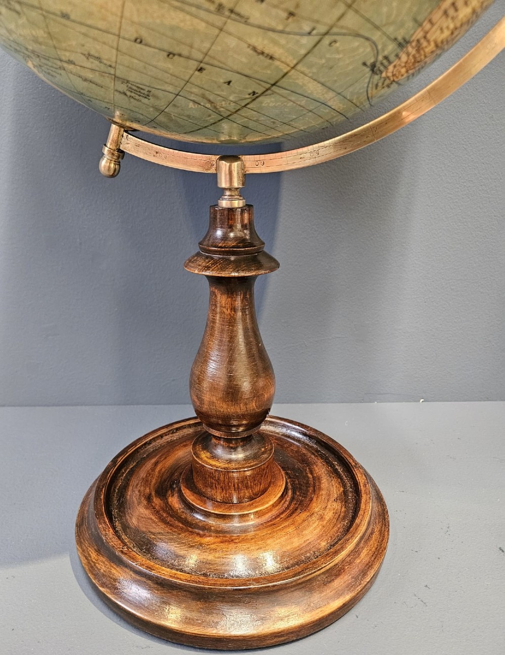 A 1920s terrestrial table globe with printed paper maps mounted on a brass semi-meridian arc and a turned dark walnut base. View VII