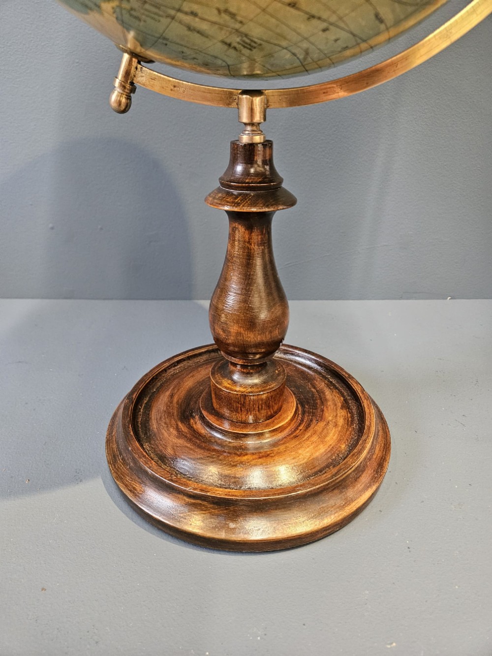 A 1920s terrestrial table globe with printed paper maps mounted on a brass semi-meridian arc and a turned dark walnut base. View VIII