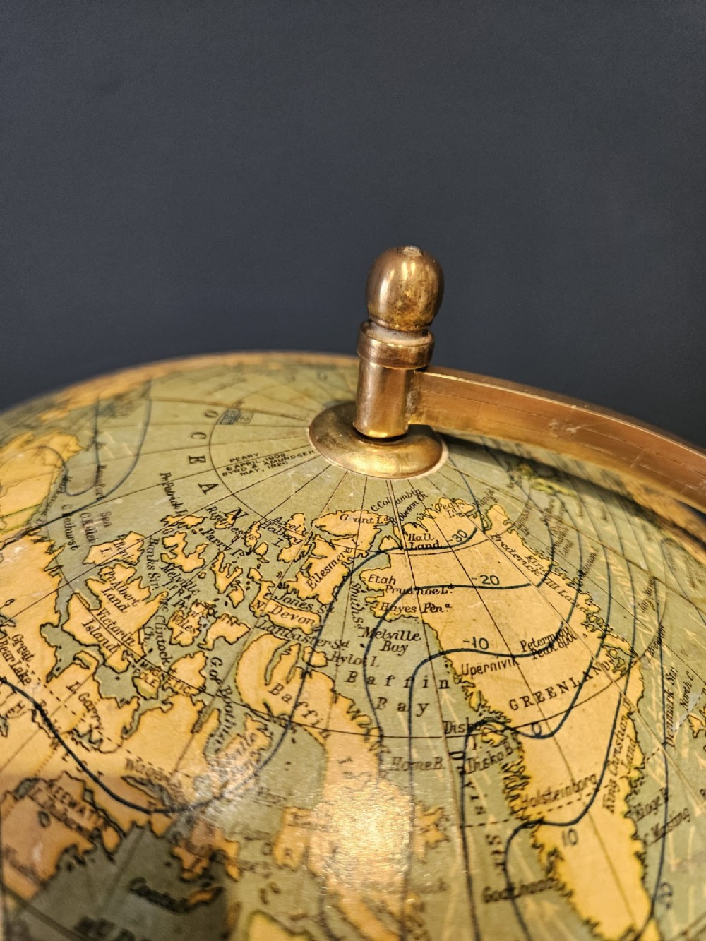 A 1920s terrestrial table globe with printed paper maps mounted on a brass semi-meridian arc and a turned dark walnut base. View XI