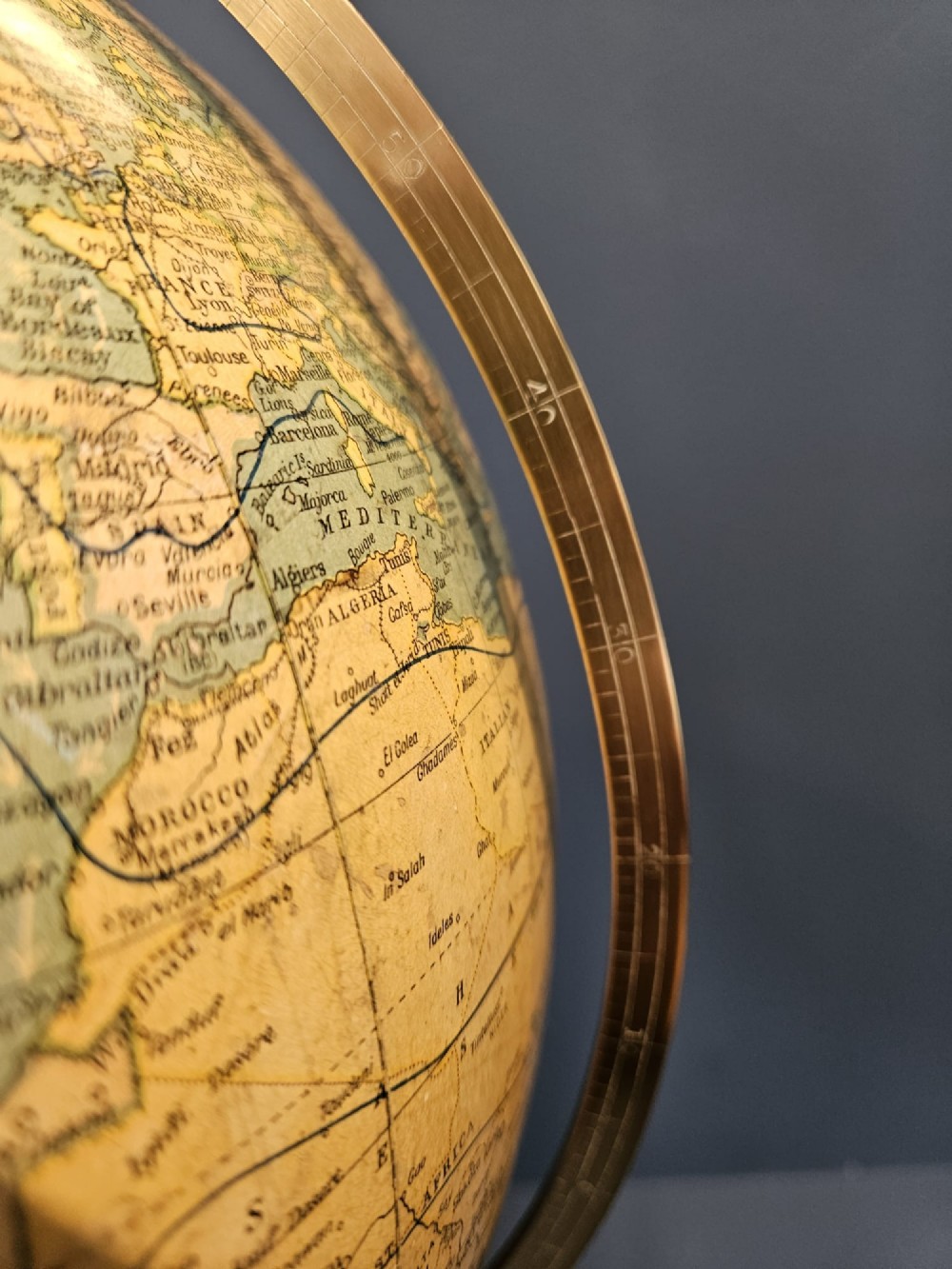 A 1920s terrestrial table globe with printed paper maps mounted on a brass semi-meridian arc and a turned dark walnut base. View XIII