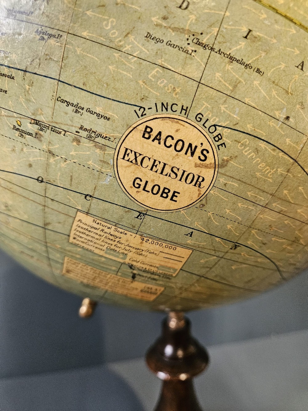 A 1920s terrestrial table globe with printed paper maps mounted on a brass semi-meridian arc and a turned dark walnut base. View XIV
