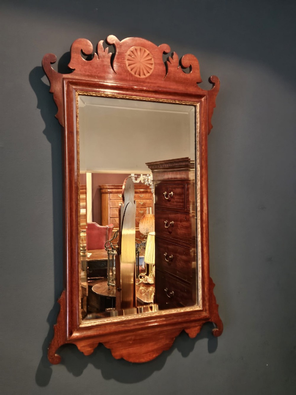 A George III mahogany fretwork wall mirror featuring a scrolled cresting with an inlaid patera roundel, a gilded sight edge, and a rectangular mirror plate. View II