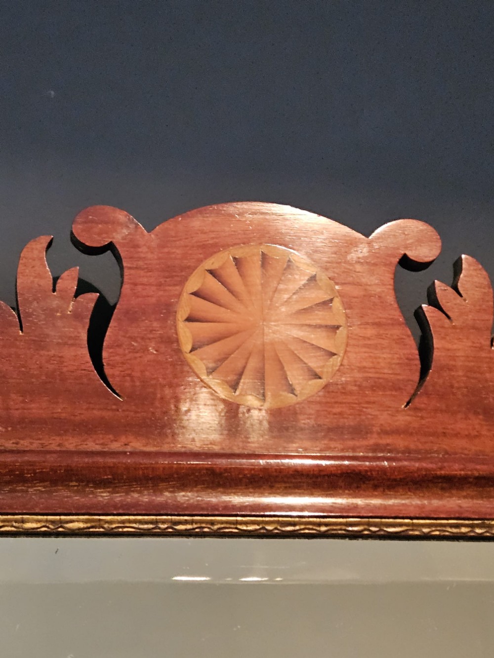 A George III mahogany fretwork wall mirror featuring a scrolled cresting with an inlaid patera roundel, a gilded sight edge, and a rectangular mirror plate. View V