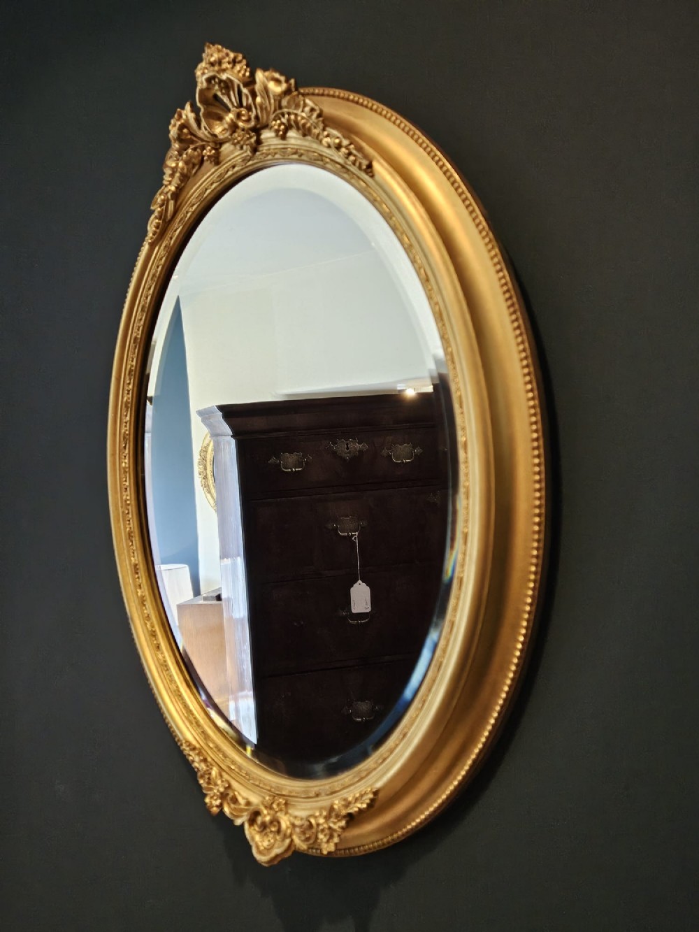 A mid-Victorian oval wall mirror featuring a giltwood frame adorned with carved cresting, beaded borders, and a bevelled mirror plate. View III