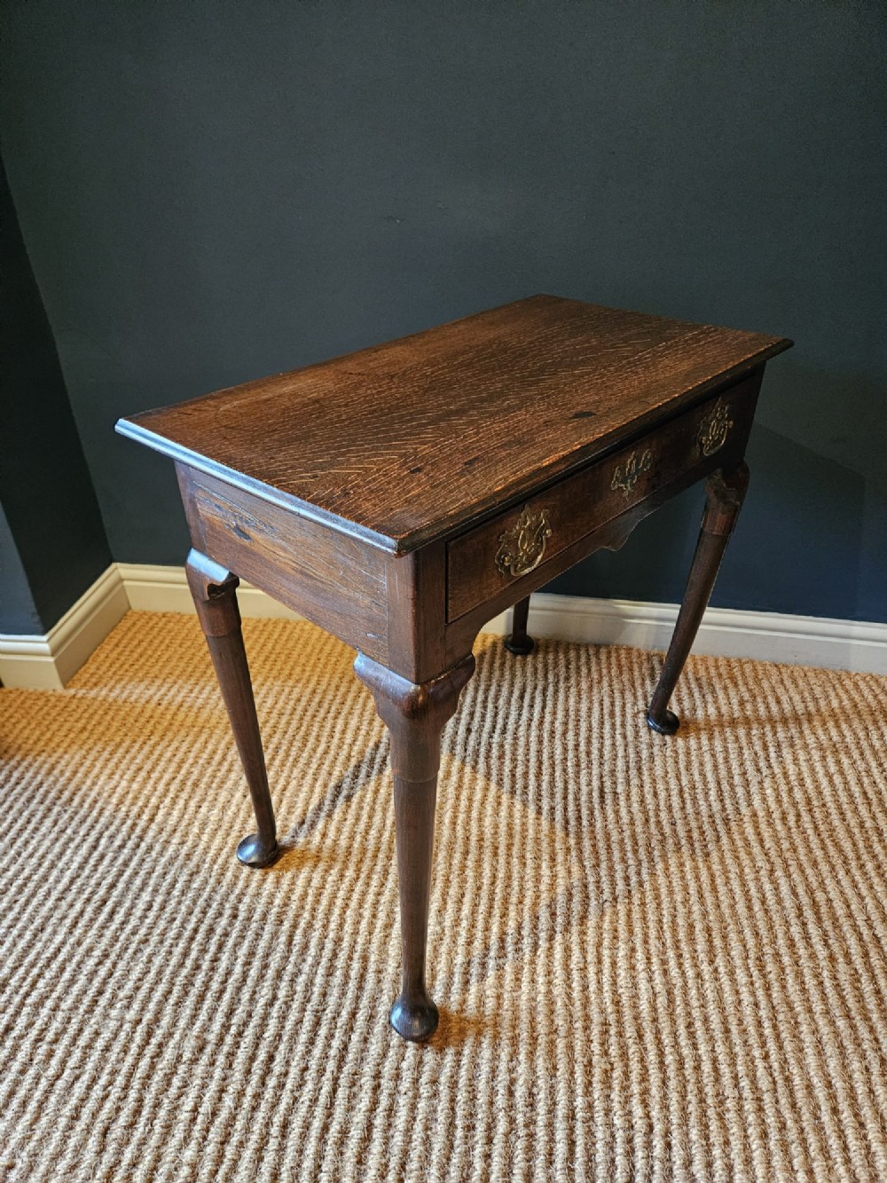 A George II dark oak side table with a single drawer, pierced brass handles, a shaped apron, and four cabriole legs terminating in pad feet. View IV