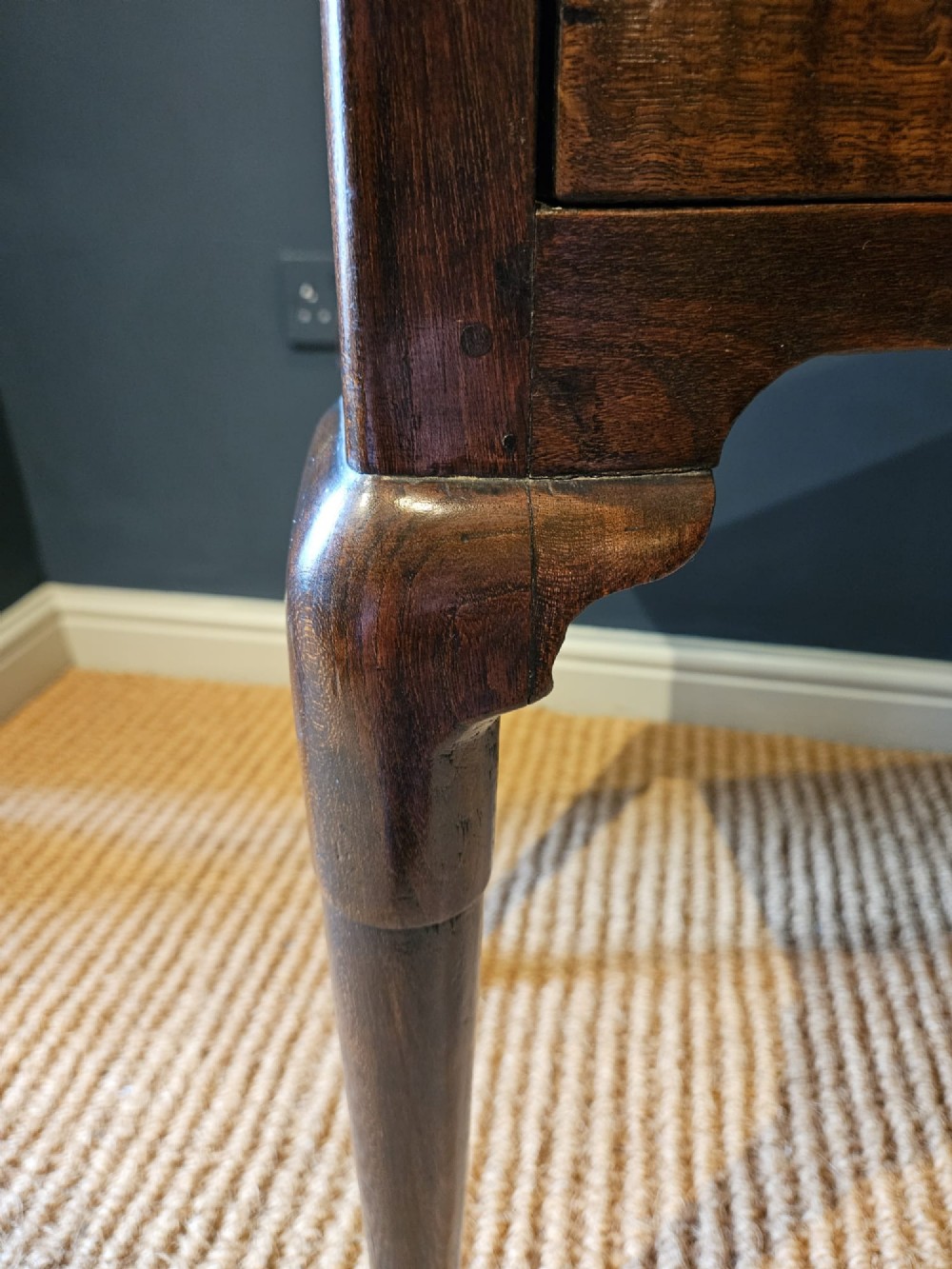 A George II dark oak side table with a single drawer, pierced brass handles, a shaped apron, and four cabriole legs terminating in pad feet. View V