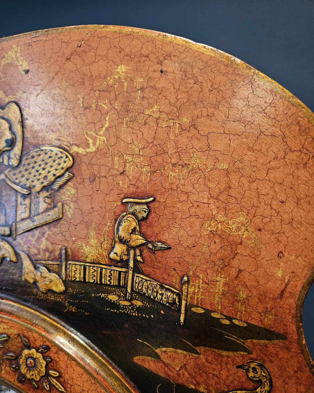 A tall 1920s Chinoiserie freestanding cheval mirror featuring an arched frame decorated with gold hand-painted Asian figures and landscapes on a warm terracotta lacquered background. View VI