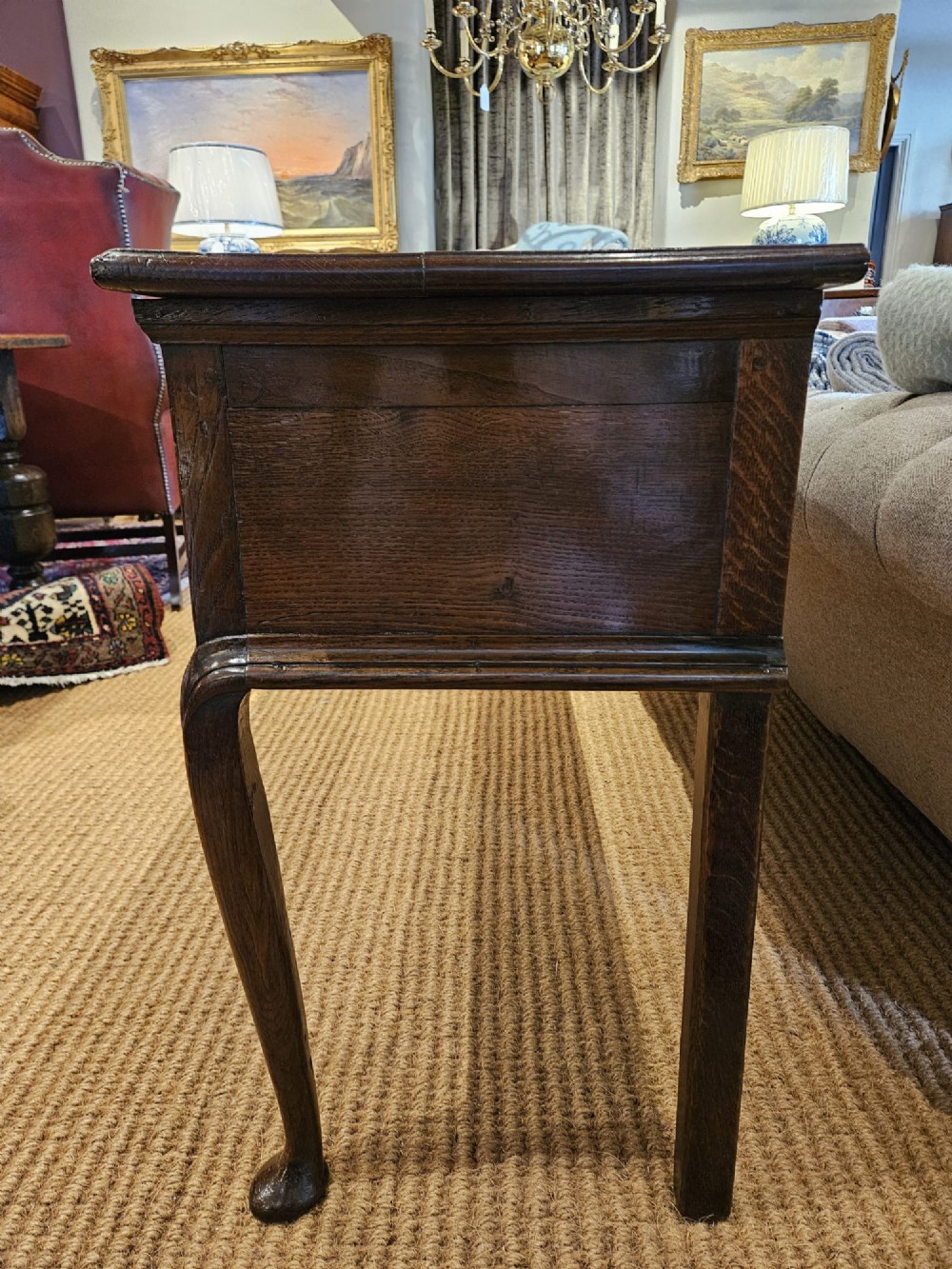 A mid-18th century George II dark oak dresser base featuring three drawers with brass swan-neck handles, raised on slender cabriole legs with pad feet. View II